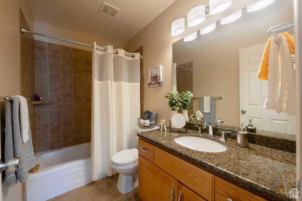 Full bathroom with tile flooring, vanity, toilet, and shower / tub combo with curtain
