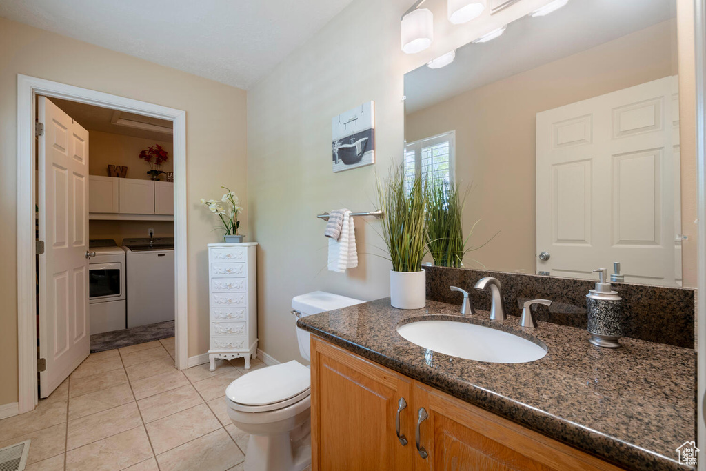 Bathroom with tile floors, independent washer and dryer, toilet, and vanity