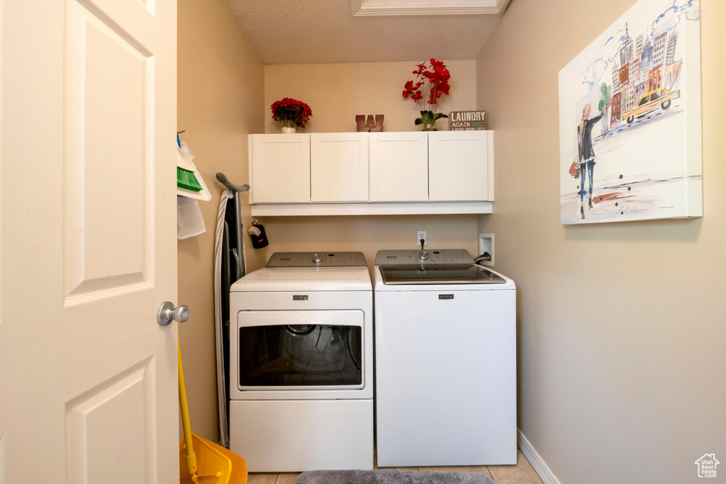 Laundry area featuring hookup for a washing machine, washing machine and clothes dryer, cabinets, and light tile floors