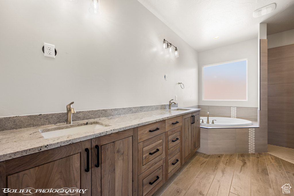 Bathroom with wood-type flooring, tiled tub, and vanity