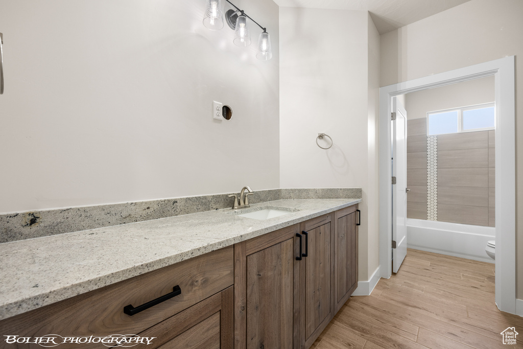 Full bathroom with toilet, shower / bathing tub combination, vanity, and hardwood / wood-style floors