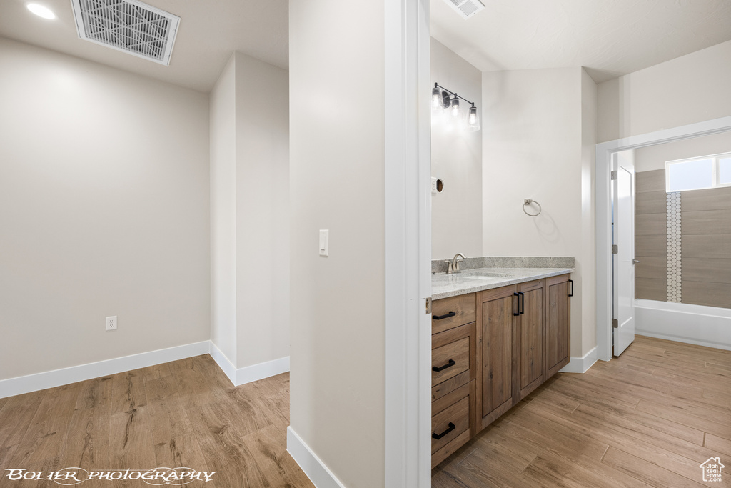 Bathroom with shower / bathing tub combination, vanity, and hardwood / wood-style flooring