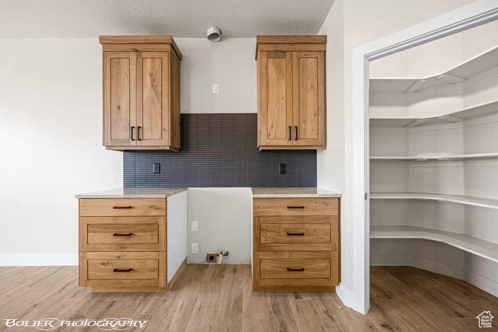 Kitchen featuring light hardwood / wood-style flooring, backsplash, and light stone countertops