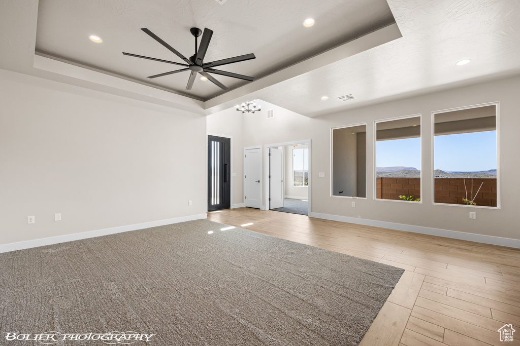 Unfurnished room with ceiling fan, a tray ceiling, and light hardwood / wood-style floors