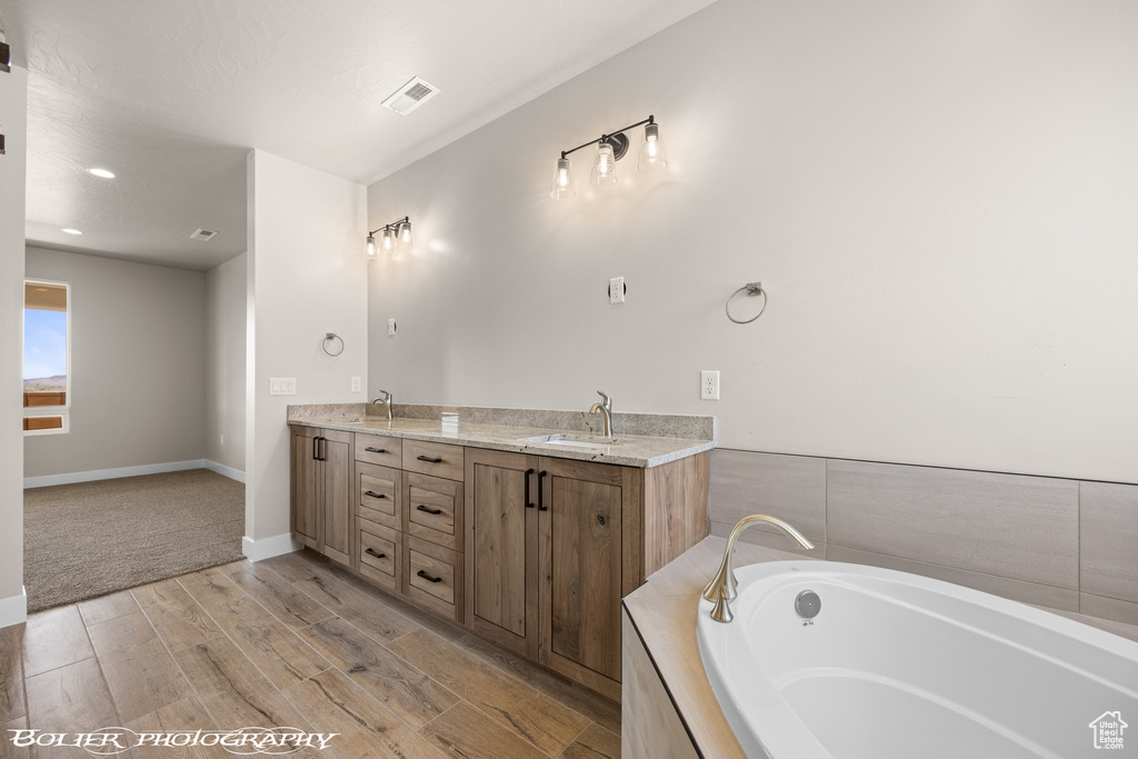 Bathroom with a tub, hardwood / wood-style floors, and dual bowl vanity