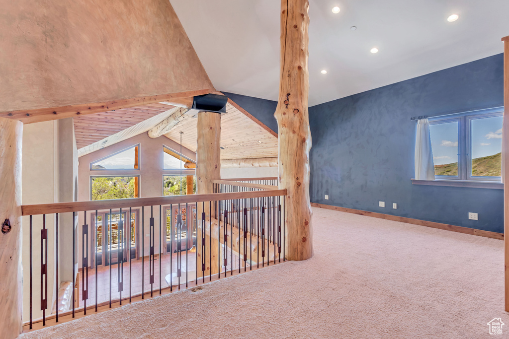 Corridor featuring carpet and vaulted ceiling with beams