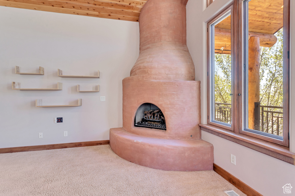 Unfurnished living room featuring carpet floors, wooden ceiling, and a fireplace