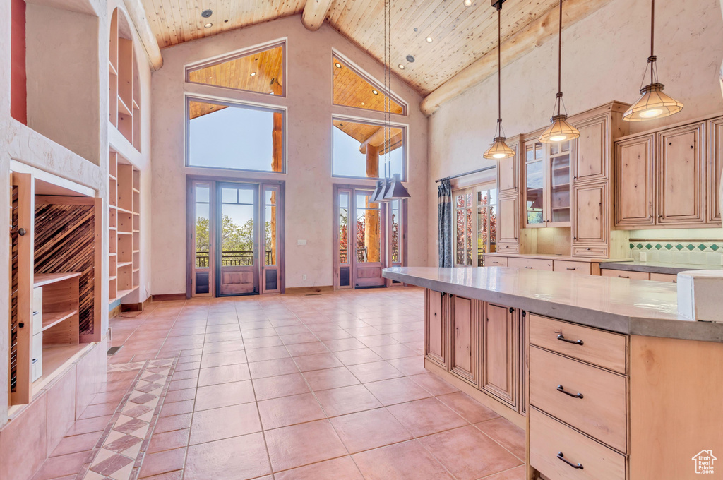 Kitchen with high vaulted ceiling, beam ceiling, light tile floors, and light brown cabinets