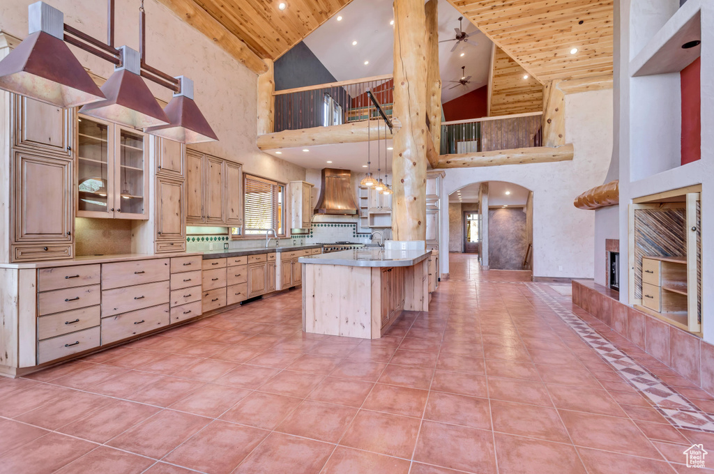 Kitchen featuring decorative light fixtures, high vaulted ceiling, tile floors, wooden ceiling, and custom range hood