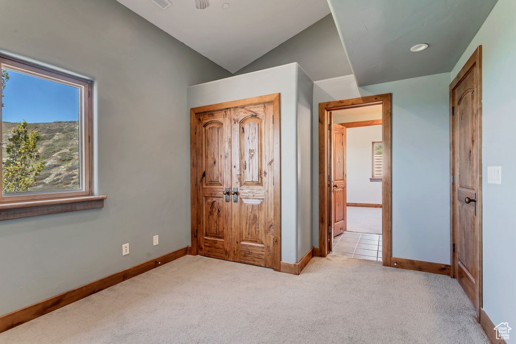 Unfurnished bedroom with light colored carpet and lofted ceiling