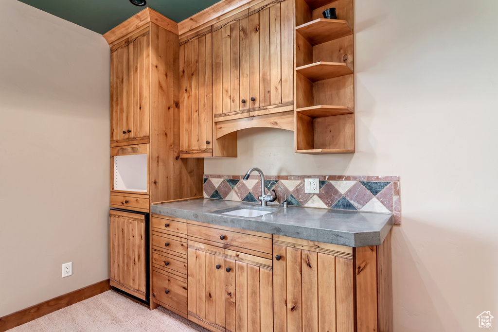 Kitchen with backsplash, light carpet, and sink