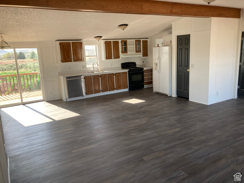 Kitchen featuring lofted ceiling with beams, white refrigerator with ice dispenser, plenty of natural light, dark hardwood / wood-style flooring, and black range with gas stovetop