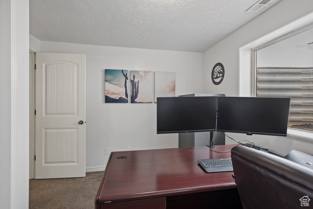 Office featuring dark carpet and a textured ceiling