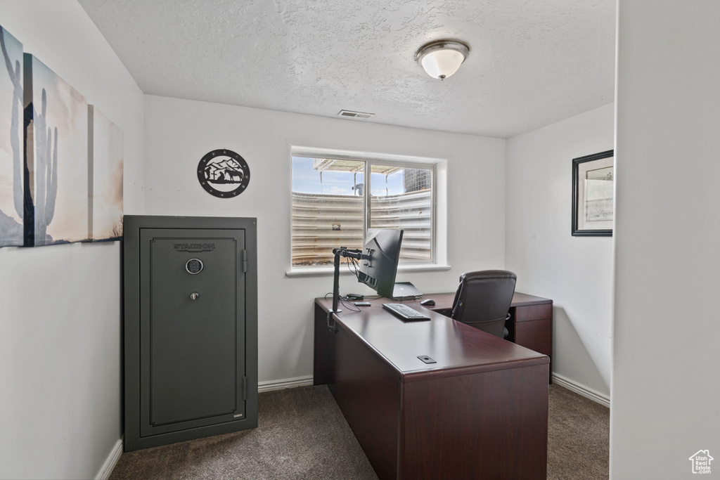 Office space with dark carpet and a textured ceiling