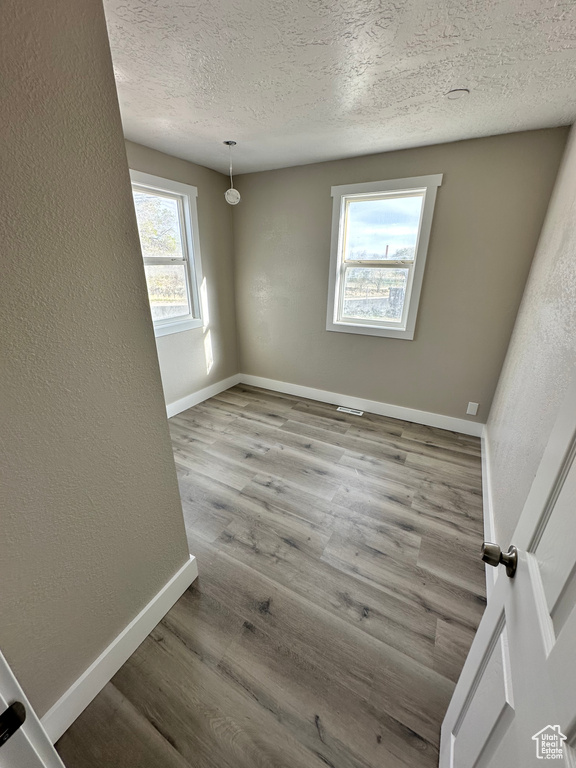Empty room with hardwood / wood-style flooring and a textured ceiling