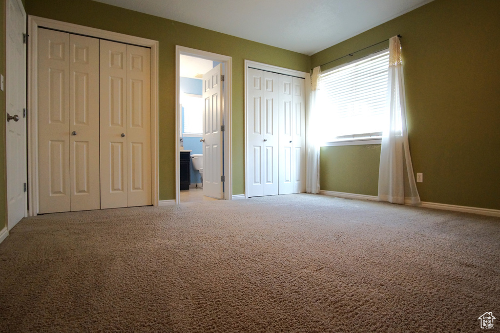 Unfurnished bedroom featuring multiple closets, carpet, and connected bathroom