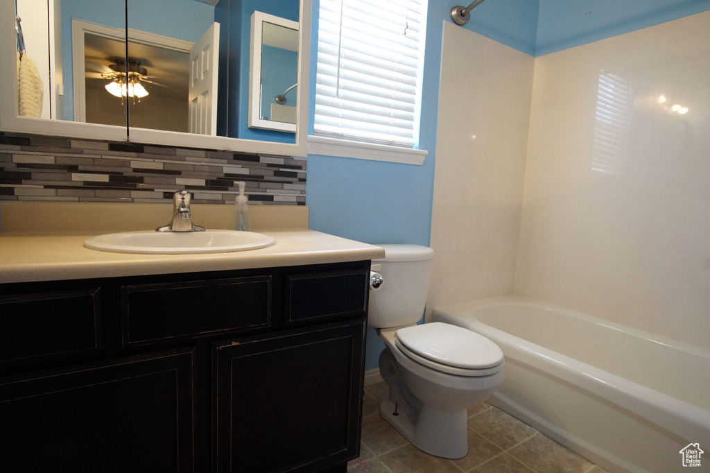 Full bathroom featuring vanity, backsplash, tile flooring, toilet, and ceiling fan