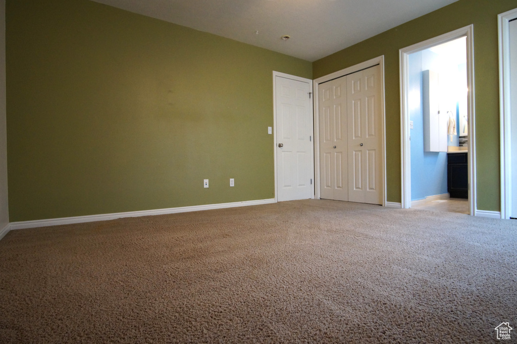 Unfurnished bedroom featuring ensuite bath and carpet floors