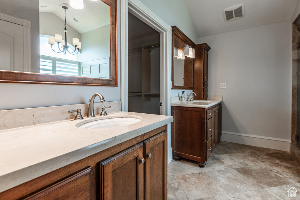 Bathroom featuring vaulted ceiling, tile floors, an inviting chandelier, and double sink vanity