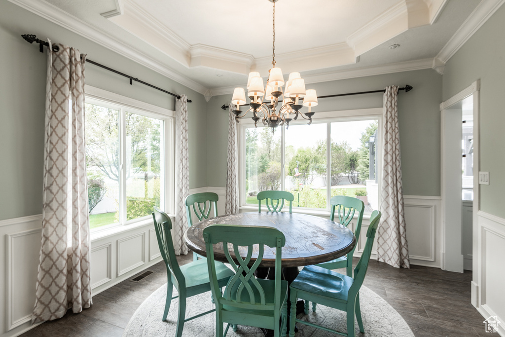 Dining space with plenty of natural light, a notable chandelier, a tray ceiling, and ornamental molding