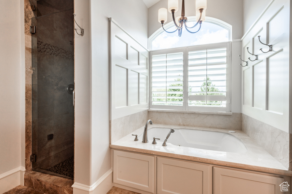 Bathroom featuring a wealth of natural light, an inviting chandelier, shower with separate bathtub, and tile flooring