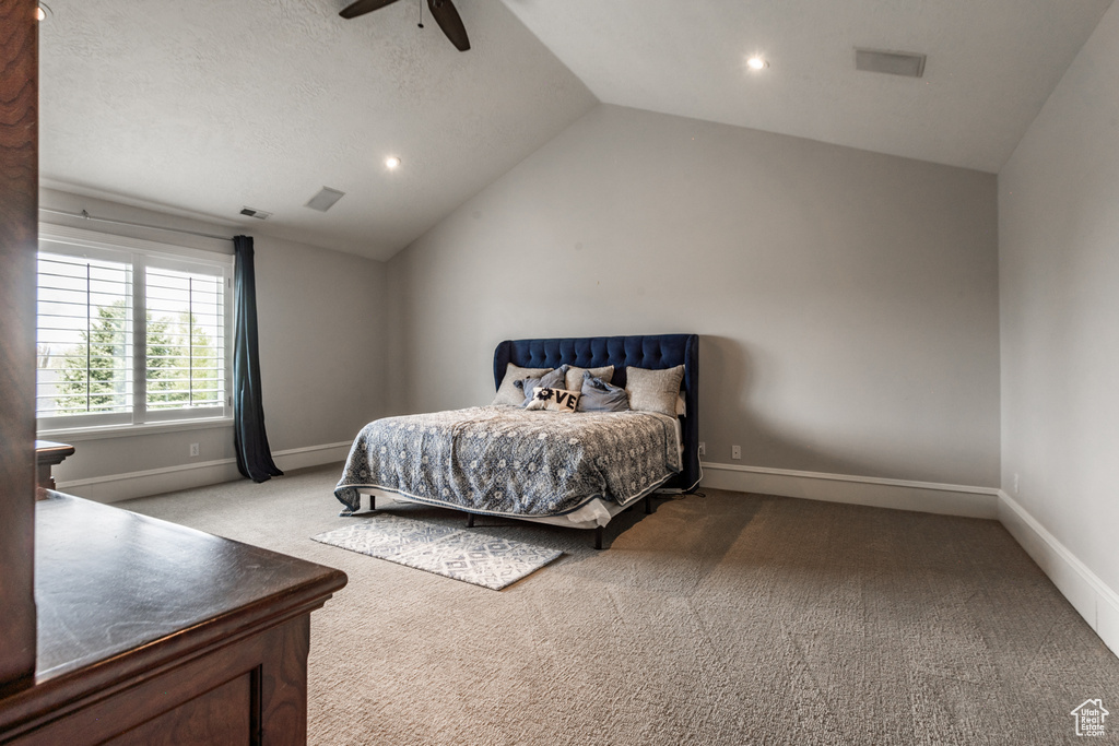 Bedroom featuring light colored carpet, vaulted ceiling, ceiling fan, and a textured ceiling