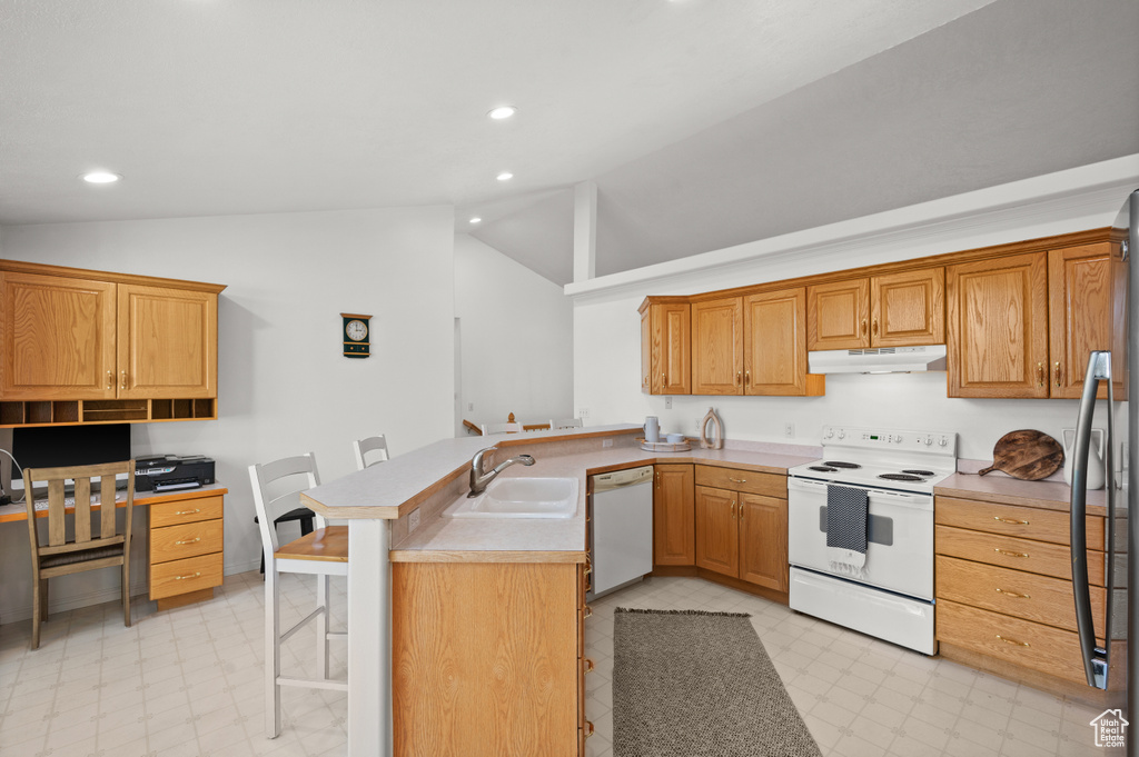 Kitchen featuring kitchen peninsula, light tile floors, white appliances, sink, and a breakfast bar