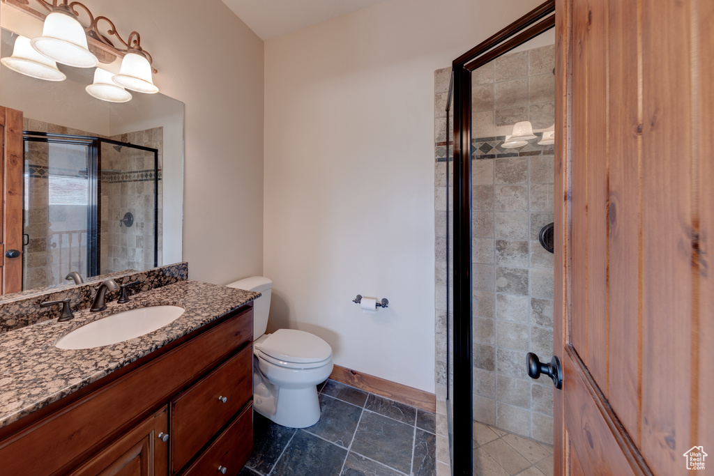 Bathroom with a shower with door, large vanity, tile floors, and toilet