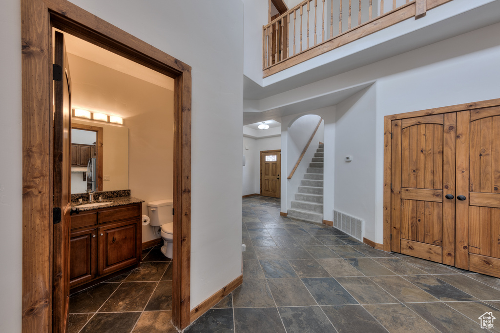 Foyer entrance with sink, a high ceiling, and dark tile floors