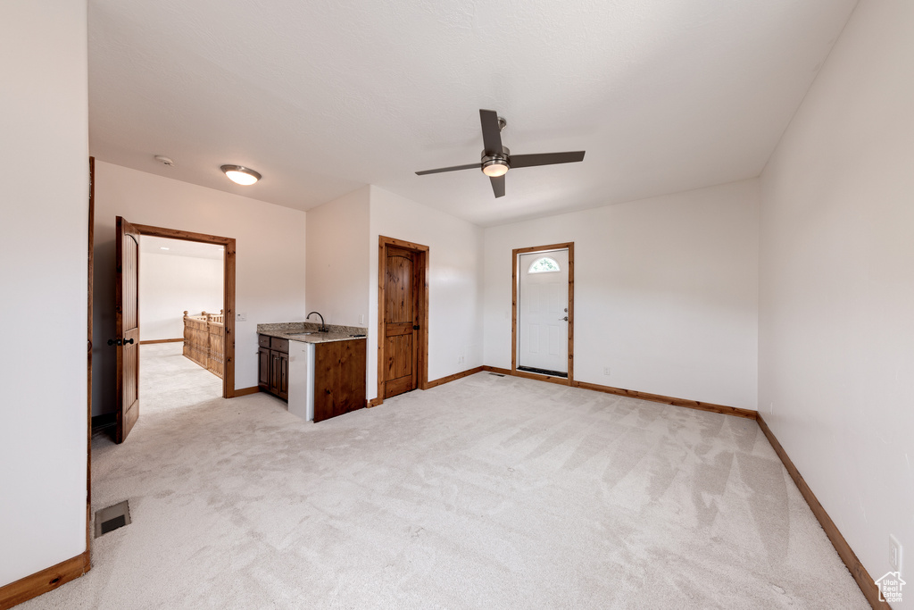 Spare room with light colored carpet, sink, and ceiling fan
