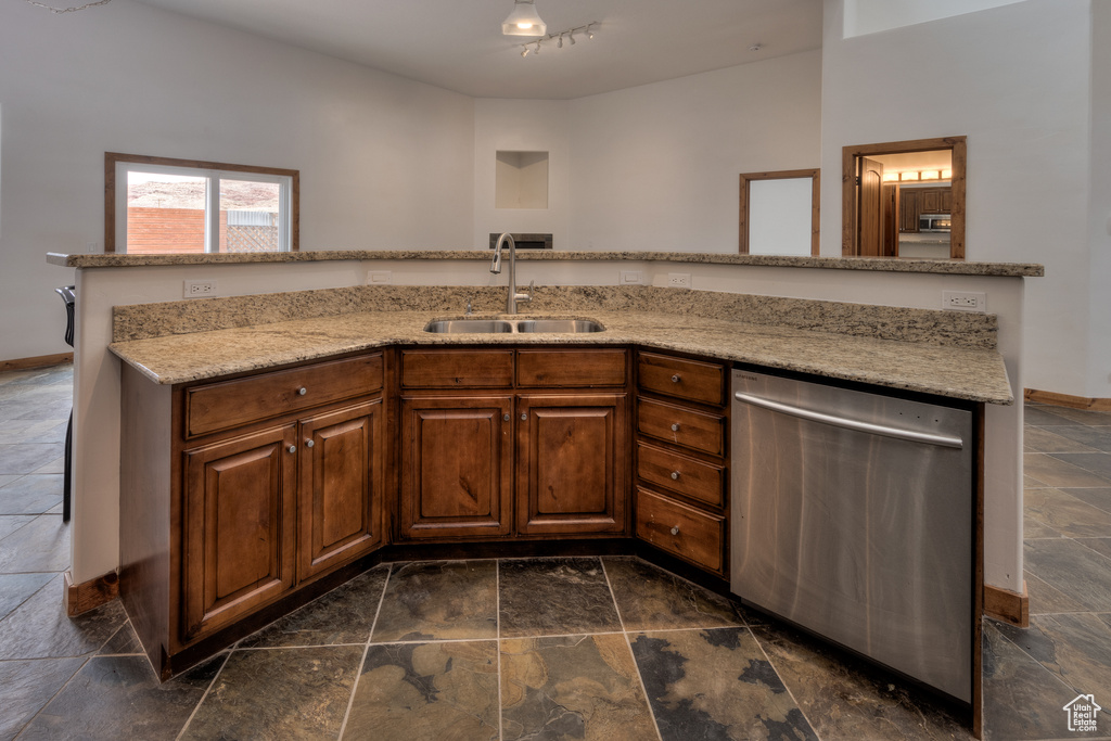 Kitchen with sink, dishwasher, dark tile flooring, and light stone countertops