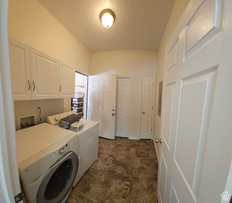Clothes washing area featuring dark tile flooring, washer and dryer, cabinets, and washer hookup
