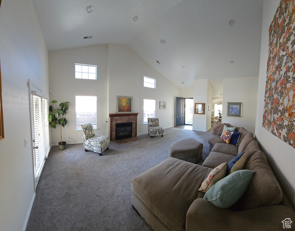 Carpeted living room featuring plenty of natural light, high vaulted ceiling, and a tile fireplace