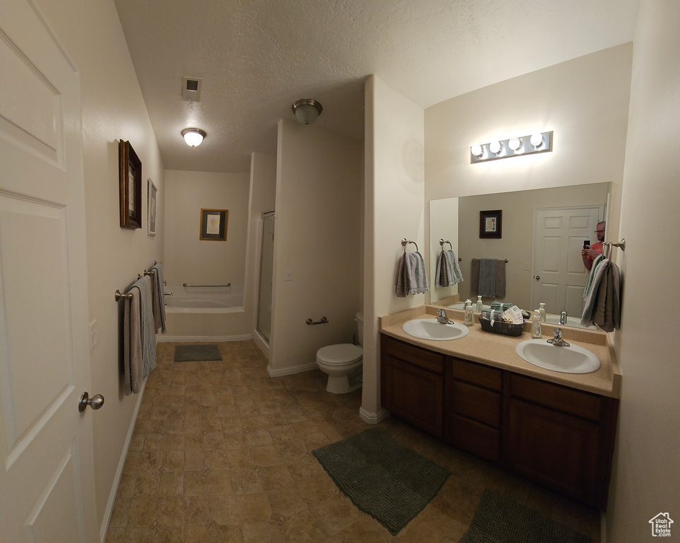 Bathroom featuring vanity with extensive cabinet space, double sink, toilet, and tile floors