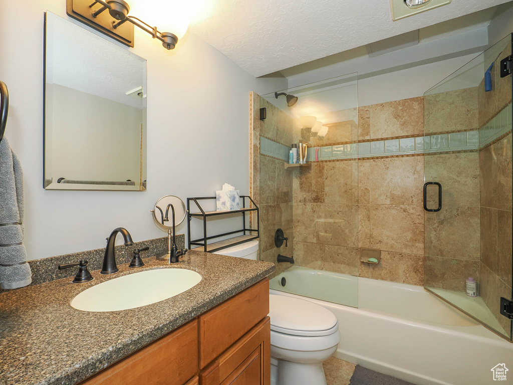 Full bathroom featuring tiled shower / bath, toilet, vanity, and a textured ceiling