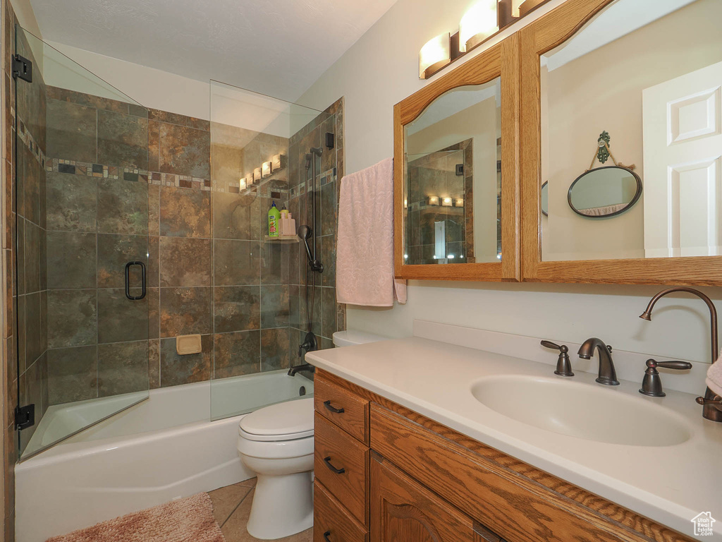 Full bathroom featuring tile floors, toilet, combined bath / shower with glass door, and vanity