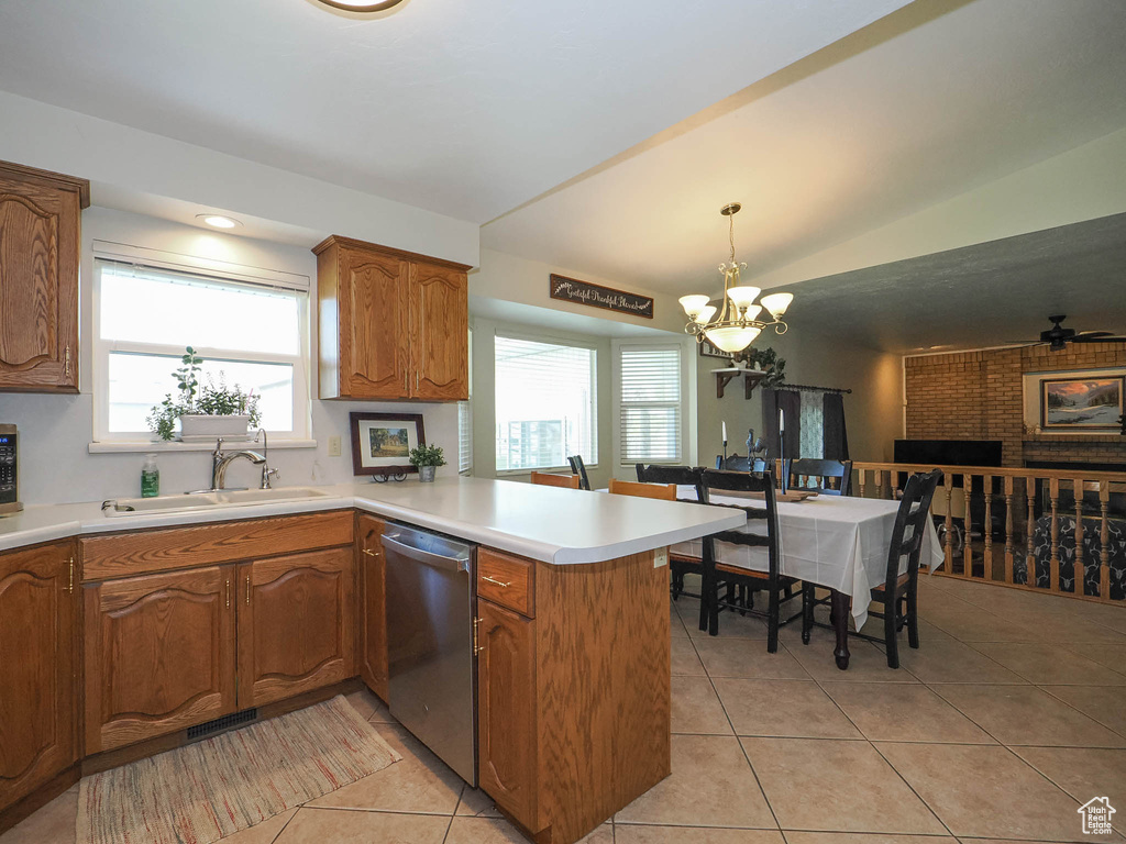 Kitchen with kitchen peninsula, dishwasher, light tile floors, and decorative light fixtures