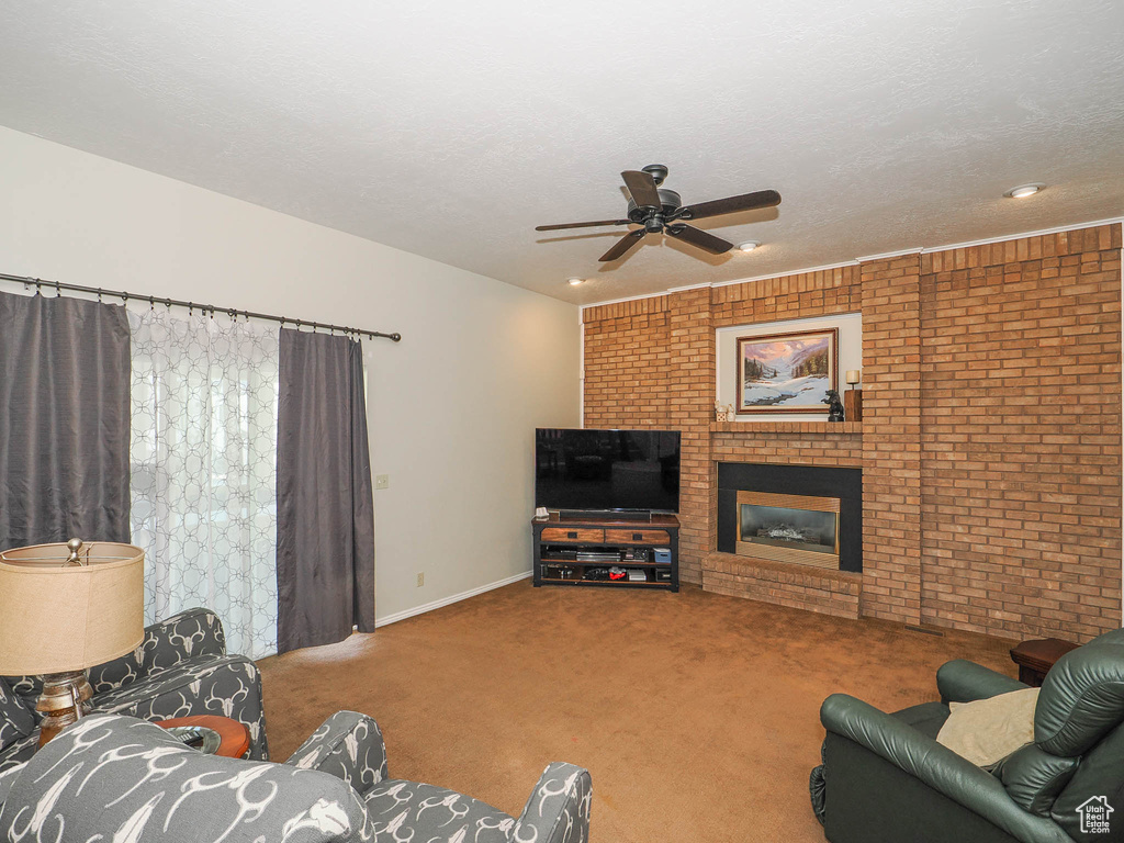Carpeted living room with brick wall, ceiling fan, and a fireplace