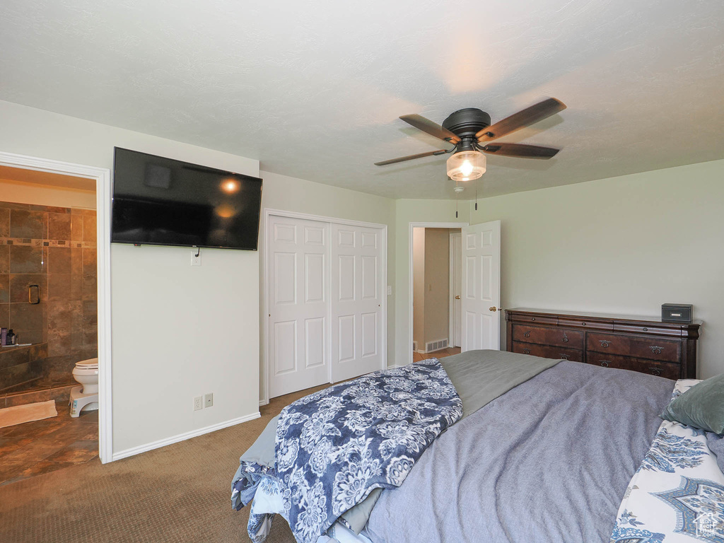 Carpeted bedroom featuring a closet, ceiling fan, and ensuite bath