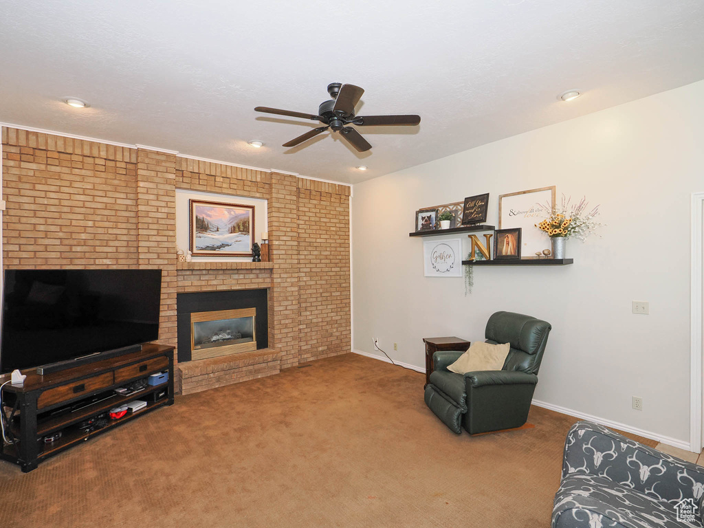 Living room featuring a fireplace, ceiling fan, brick wall, and carpet flooring