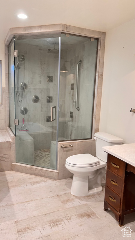 Bathroom featuring a shower with door, toilet, tile floors, and vanity