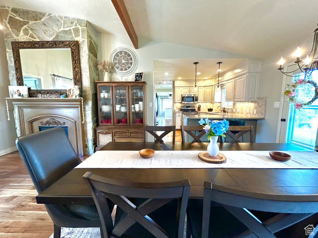 Dining space featuring sink, lofted ceiling with beams, and light wood-type flooring