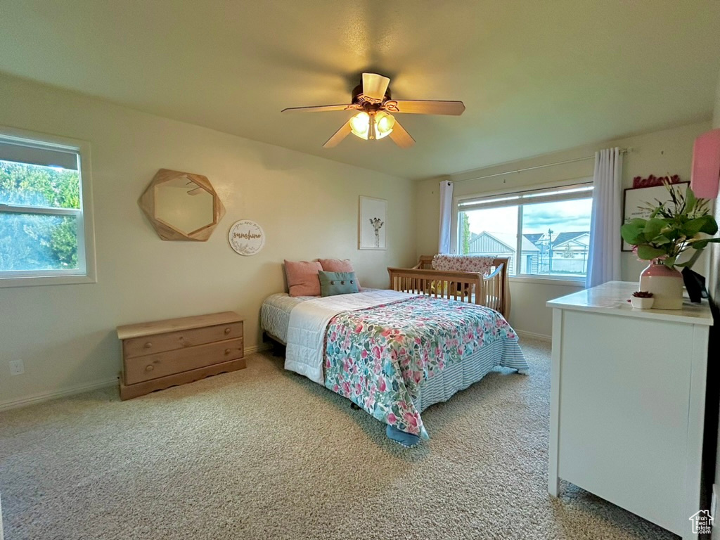 Bedroom with carpet floors, ceiling fan, and multiple windows