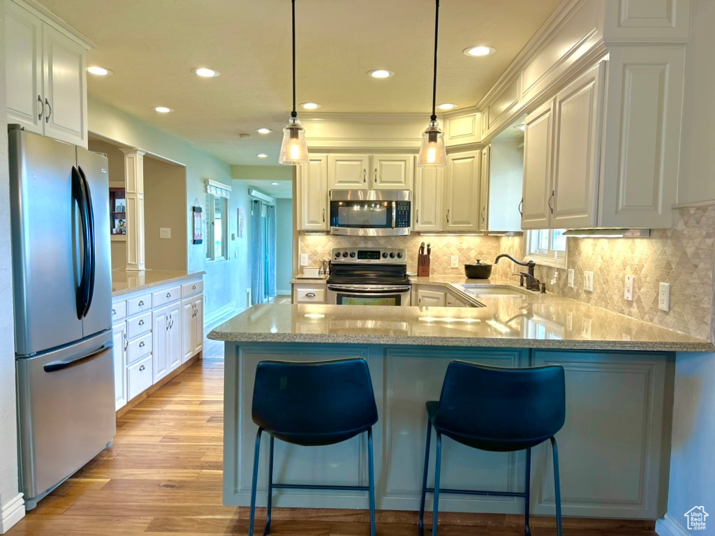 Kitchen with light hardwood / wood-style flooring, stainless steel appliances, white cabinetry, and sink