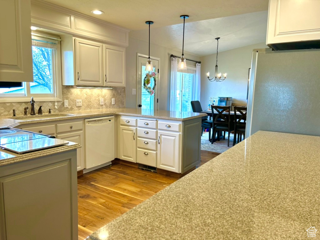 Kitchen with white appliances, light hardwood / wood-style flooring, white cabinetry, an inviting chandelier, and sink