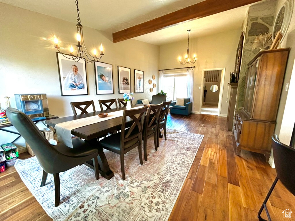 Dining room featuring dark hardwood / wood-style flooring, beam ceiling, and a notable chandelier