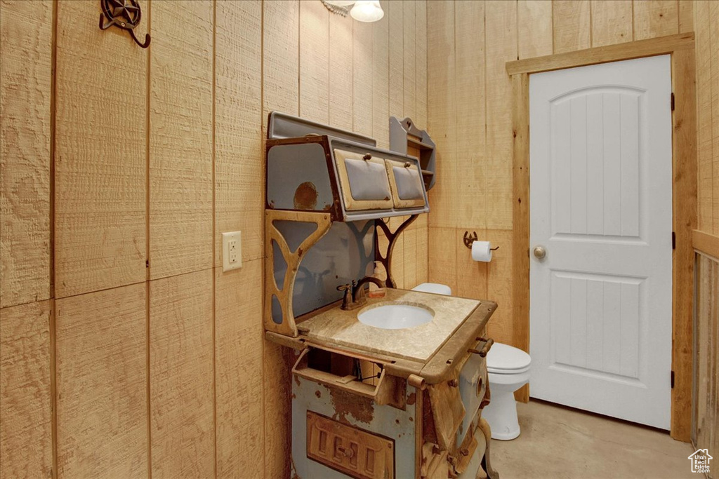 Bathroom featuring vanity, wooden walls, and toilet