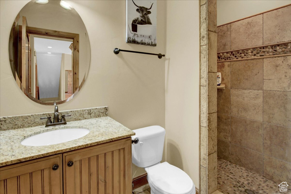 Bathroom with tiled shower, toilet, and vanity