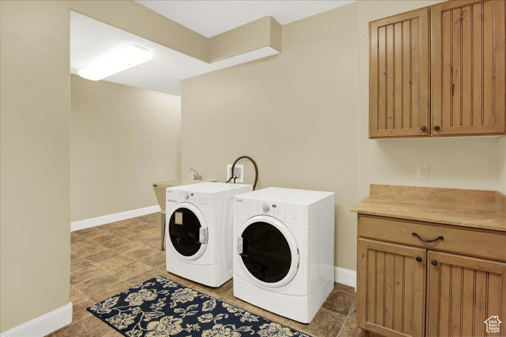 Clothes washing area featuring tile flooring, sink, cabinets, and washer and clothes dryer