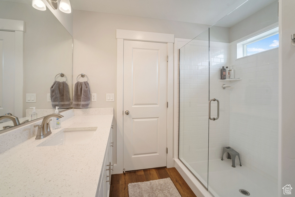 Bathroom with hardwood / wood-style flooring, an enclosed shower, and vanity